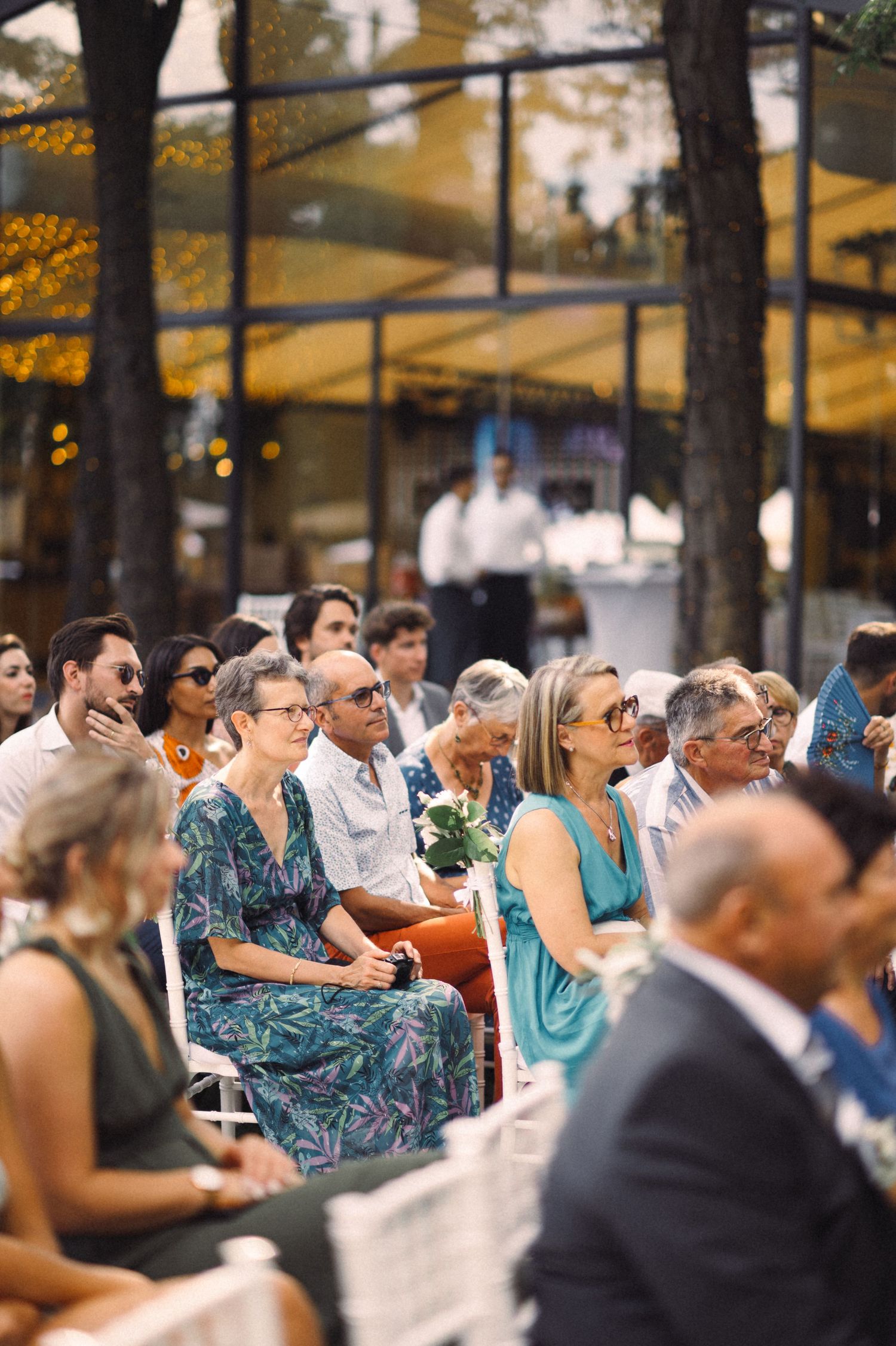 Wedding guests seated outdoors watching the ceremony under golden evening light.
