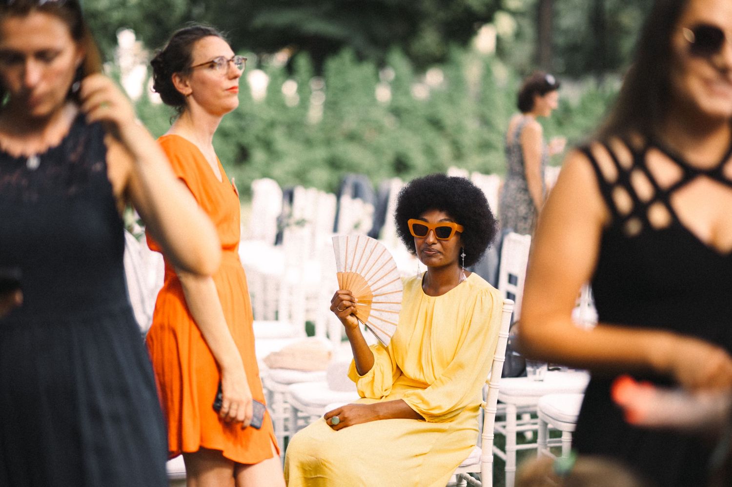 Guests in colorful attire enjoying a summer outdoor wedding celebration.