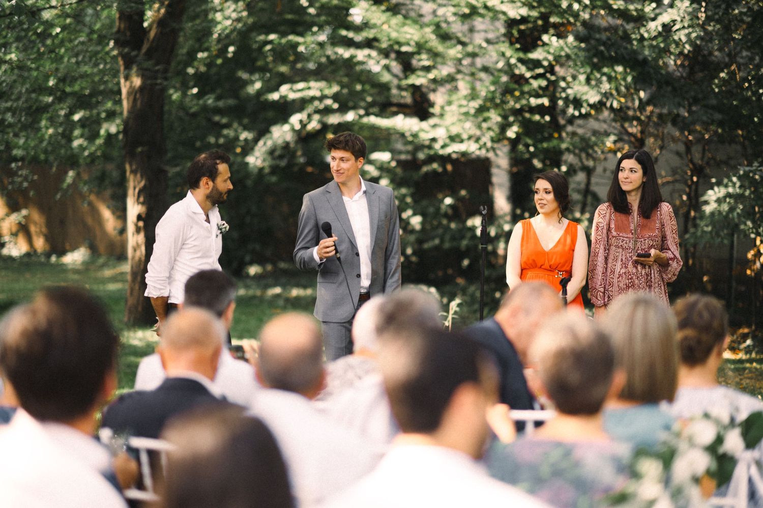 Guests gathered for an outdoor wedding ceremony in a wooded setting.