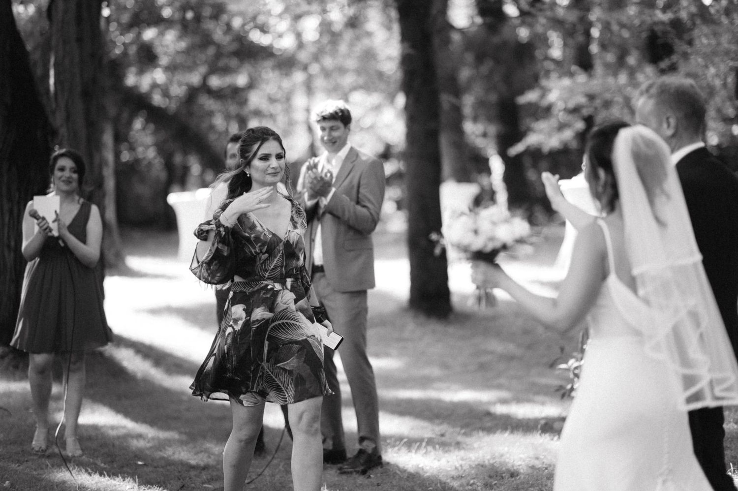 Black and white photo of wedding ceremony guests watching and taking pictures outdoors.