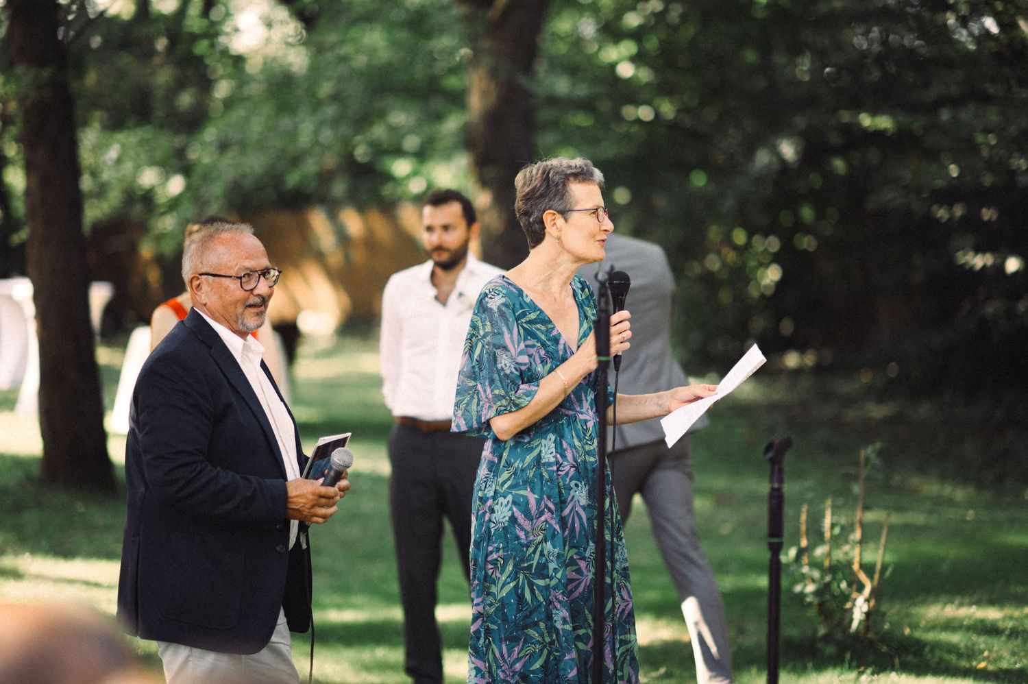 Outdoor ceremony speakers share readings during a summer garden event.