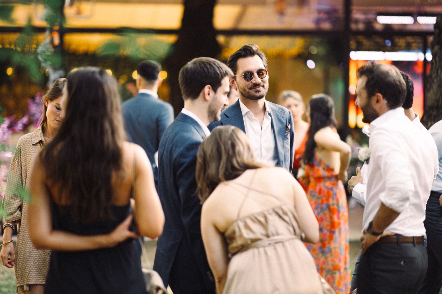 Guests socializing at an outdoor wedding reception in formal attire.