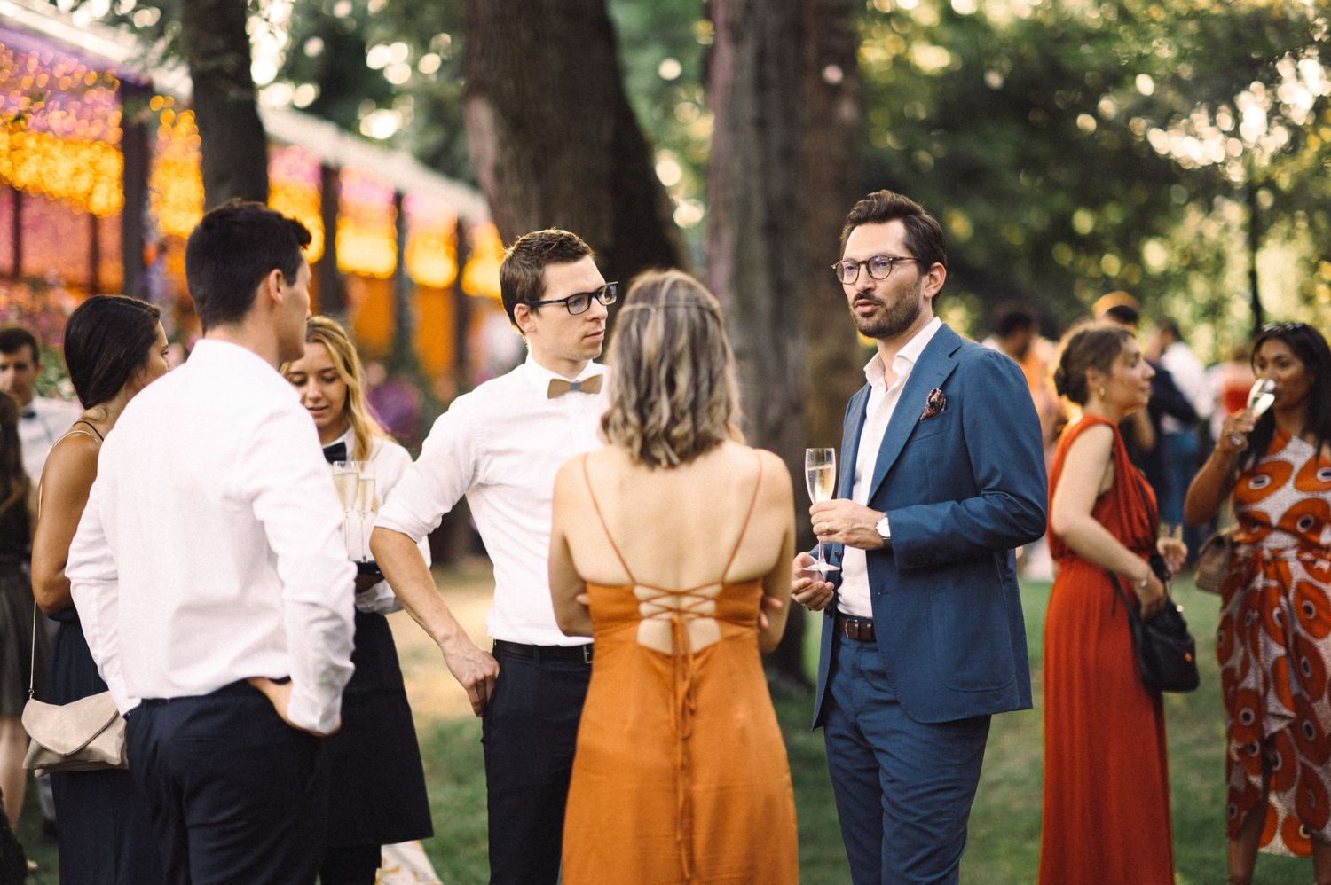 Guests enjoying an outdoor evening celebration with warm lighting and festive atmosphere at a garden party.