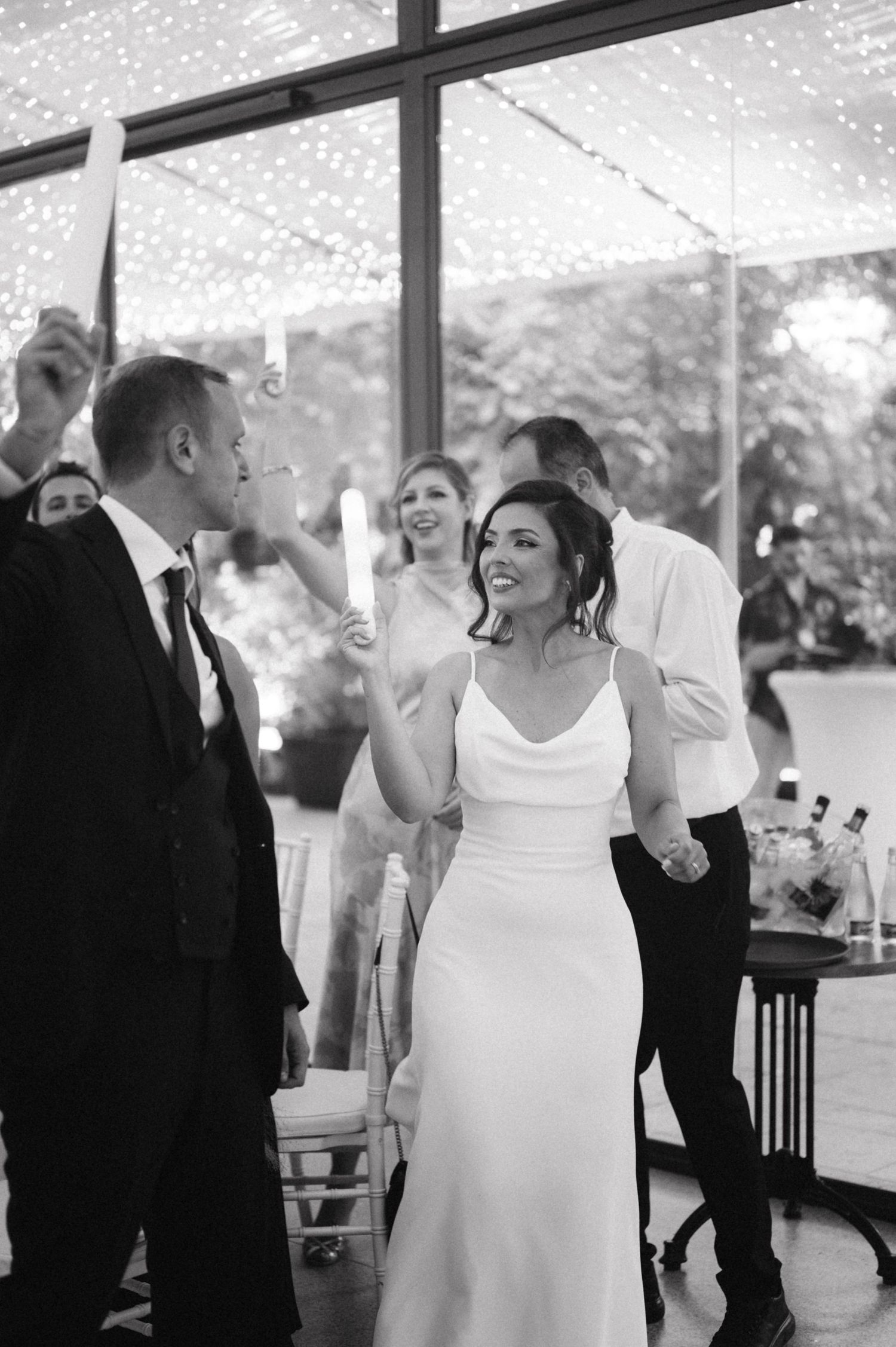 Celebration moment at a wedding reception with guests dancing underneath string lights.