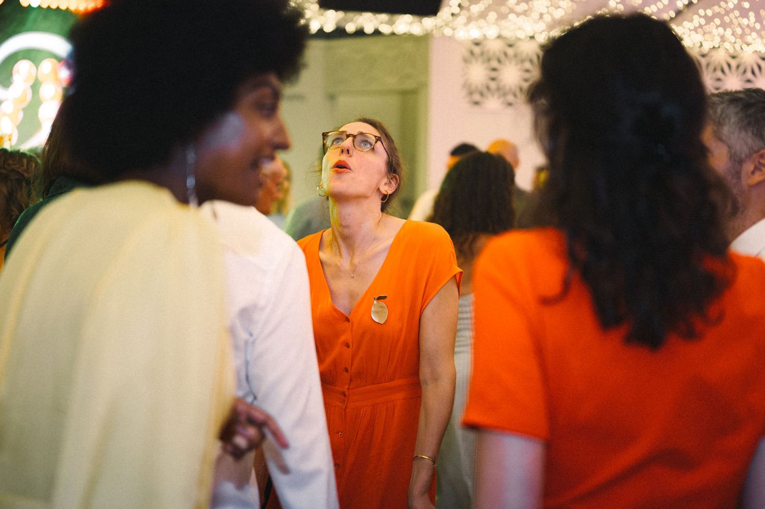 Party guests in vibrant orange attire dancing and enjoying themselves at a celebration.