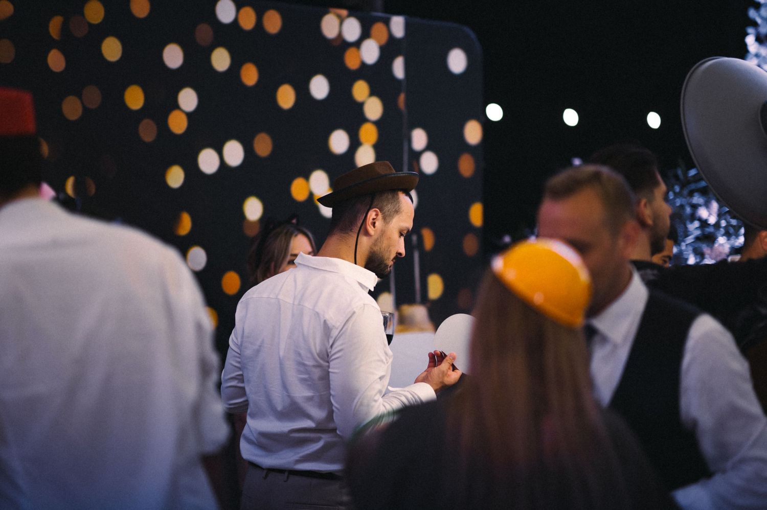 Evening celebration with bokeh lights and guests mingling in dimly lit atmosphere.