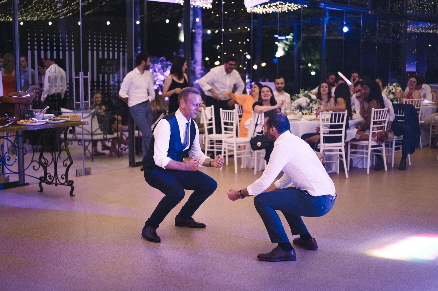 Two people perform an energetic dance move on an illuminated dance floor.