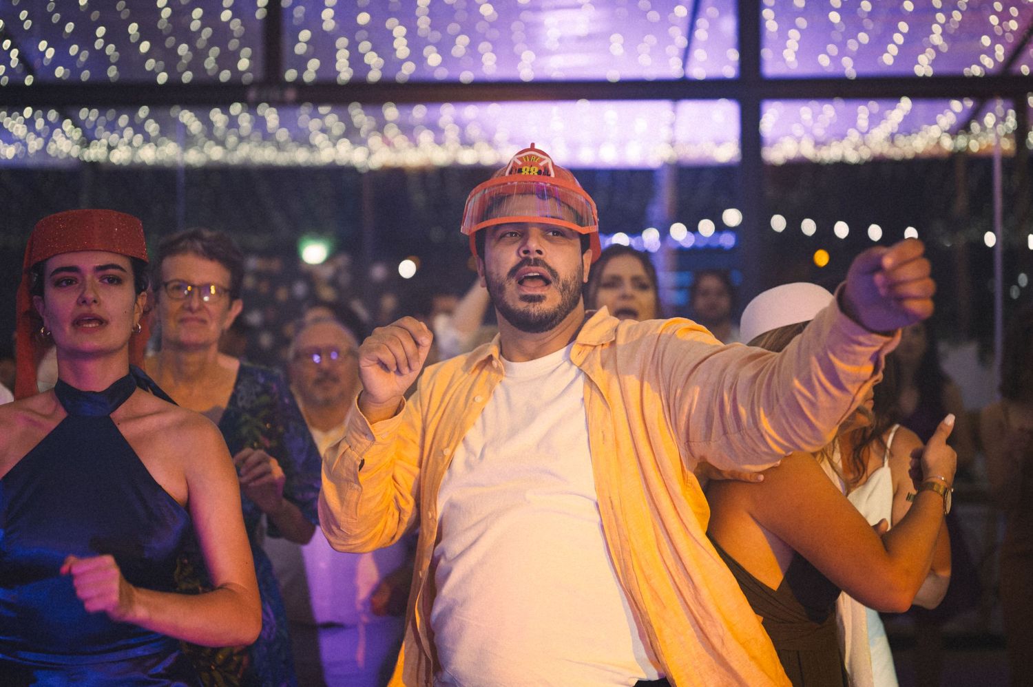 Person in yellow jacket dancing enthusiastically at a nighttime event.