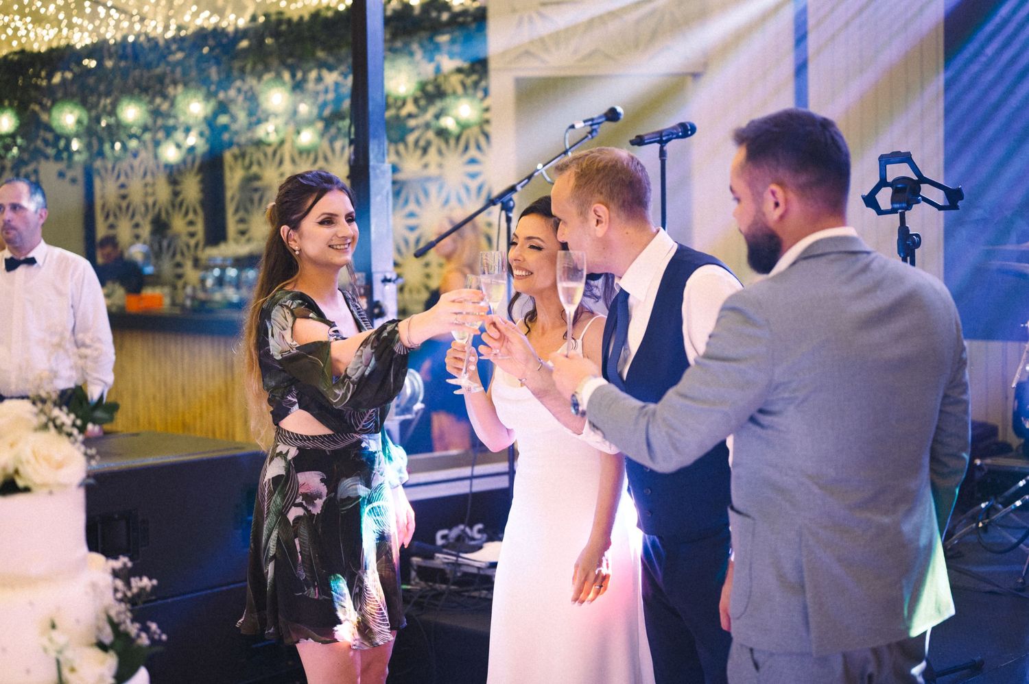 Live band performing at wedding reception with stage lighting and decorative backdrop.