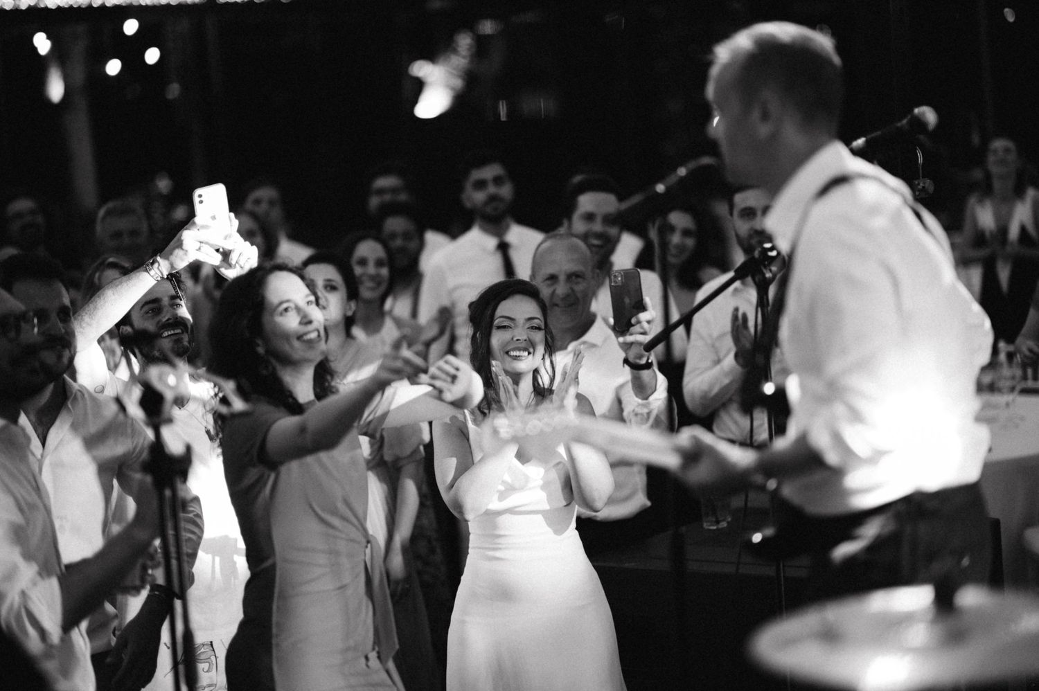 Black and white photo of wedding celebration with guests dancing and enjoying live music.