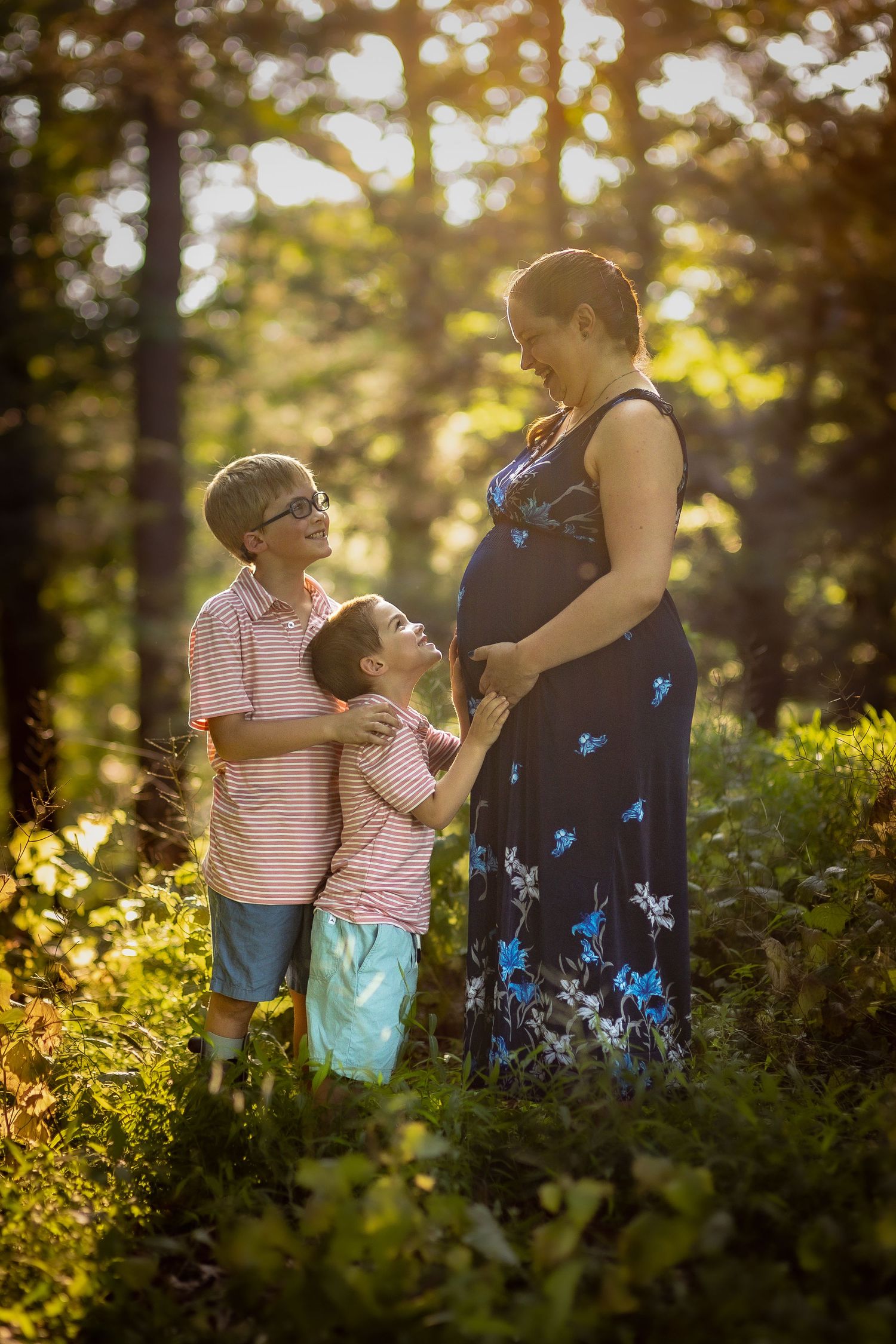 An expectant mother shares a moment with her other children as they hug her belly