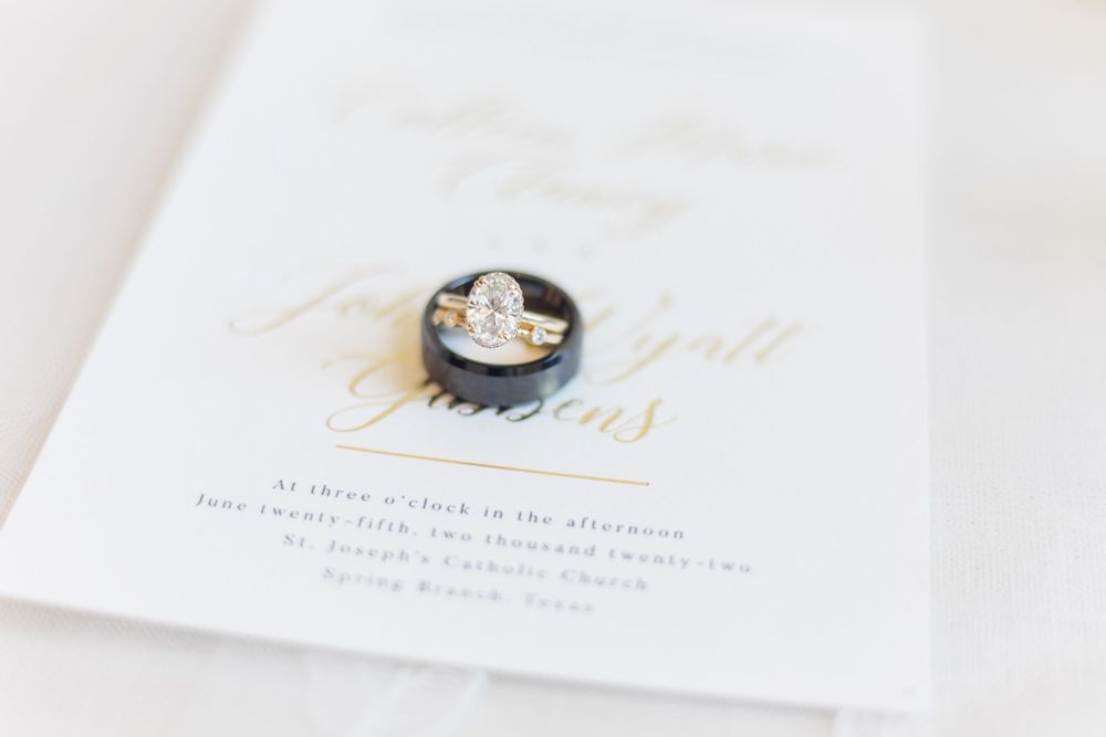 A vintage cameo brooch rests elegantly on a white wedding invitation with gold text.