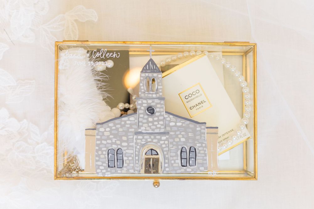 An artistic gold-framed illustration of a church building displayed as wedding decor.