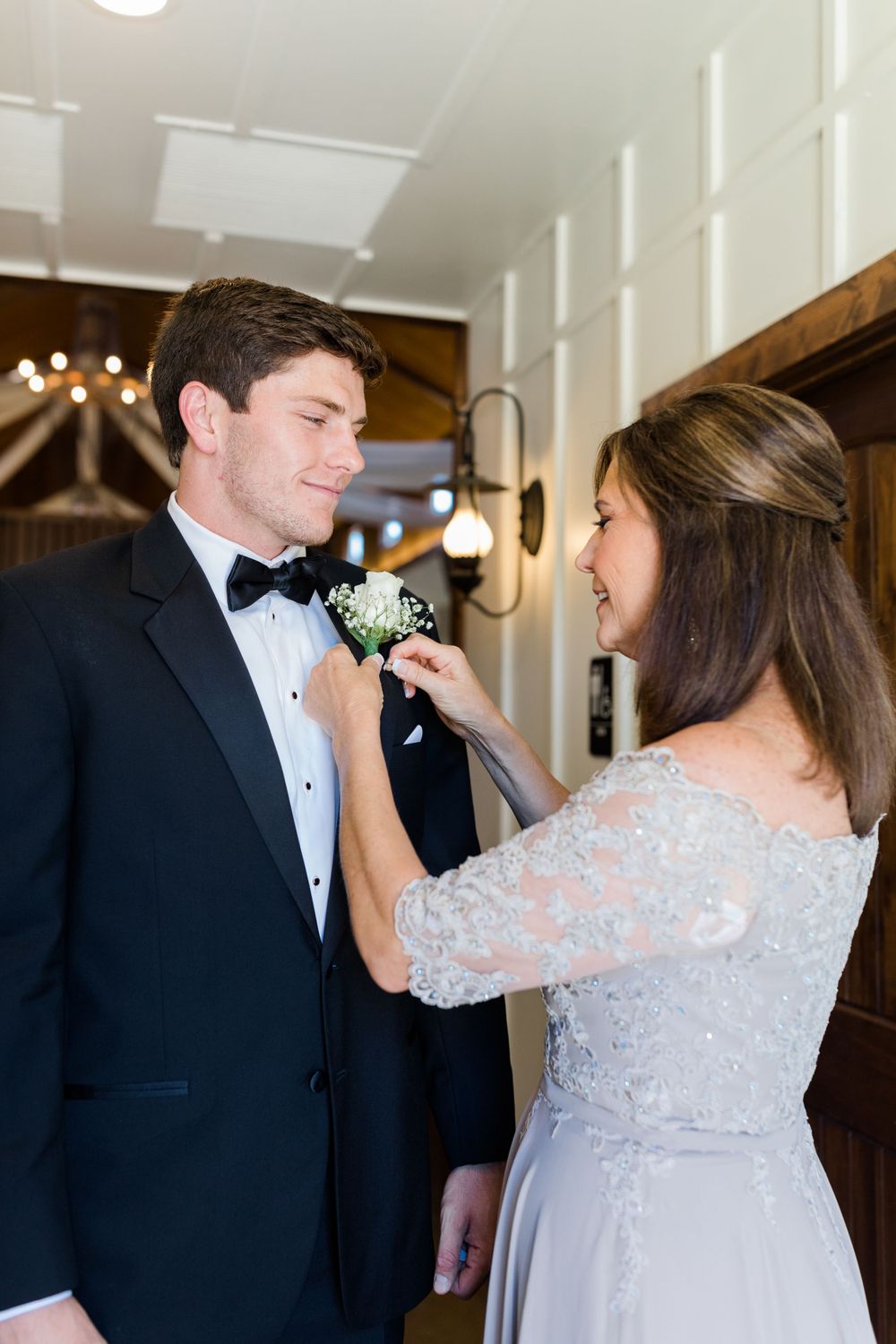 A boutonniere pinning moment between formal attire during wedding preparations.