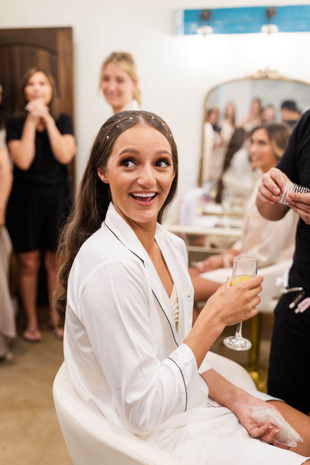 A joyful moment during wedding preparations with champagne and laughter in the bridal suite.