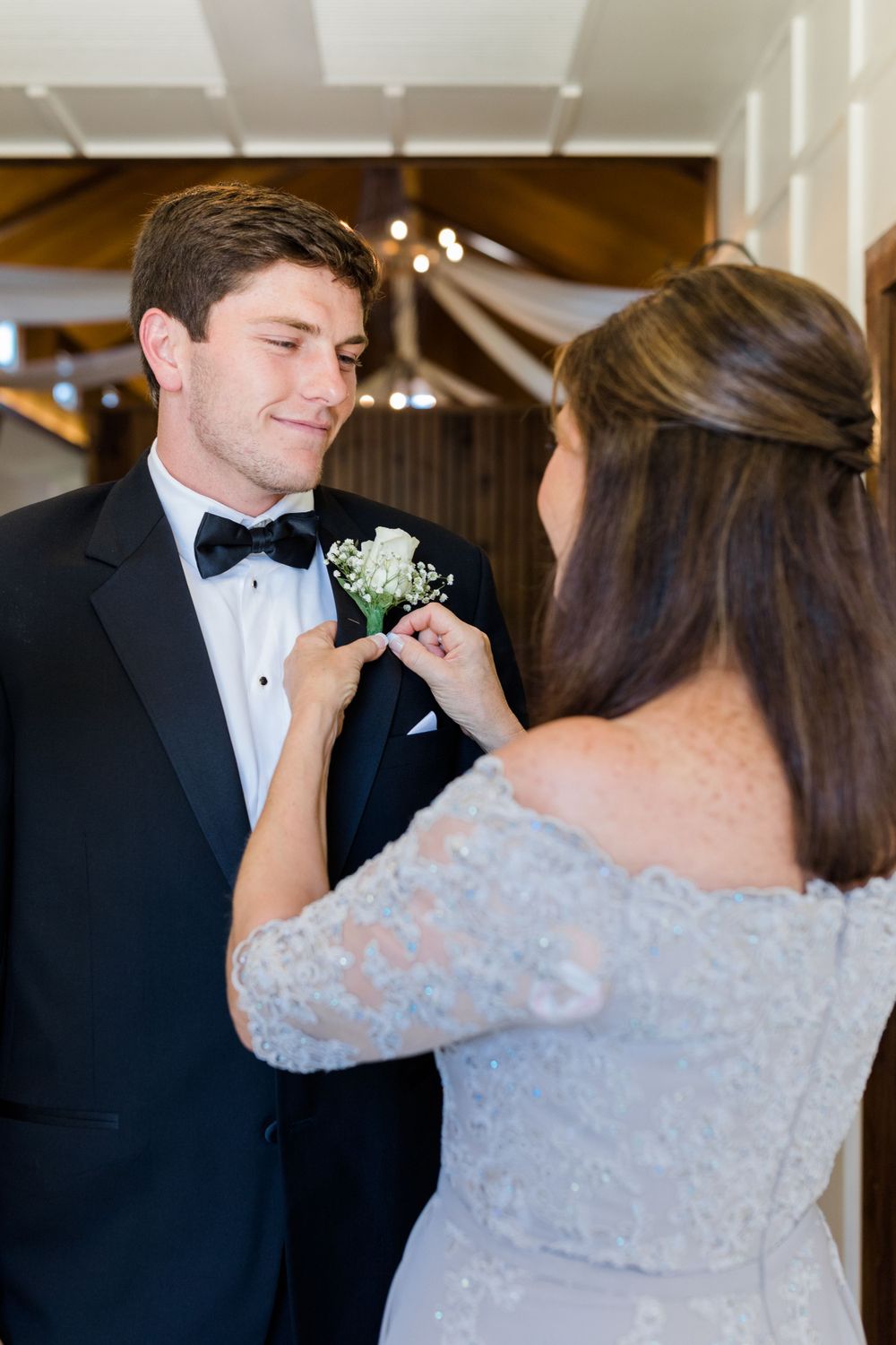 Intimate moment of boutonniere pinning in an elegantly decorated wedding venue.