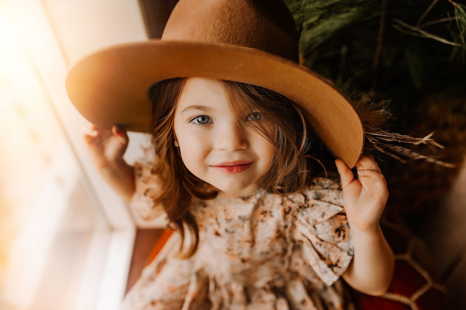 A warm-toned photo shows a small child wearing a brown wide-brimmed hat and floral dress in natural lighting in Columbia, Missouri