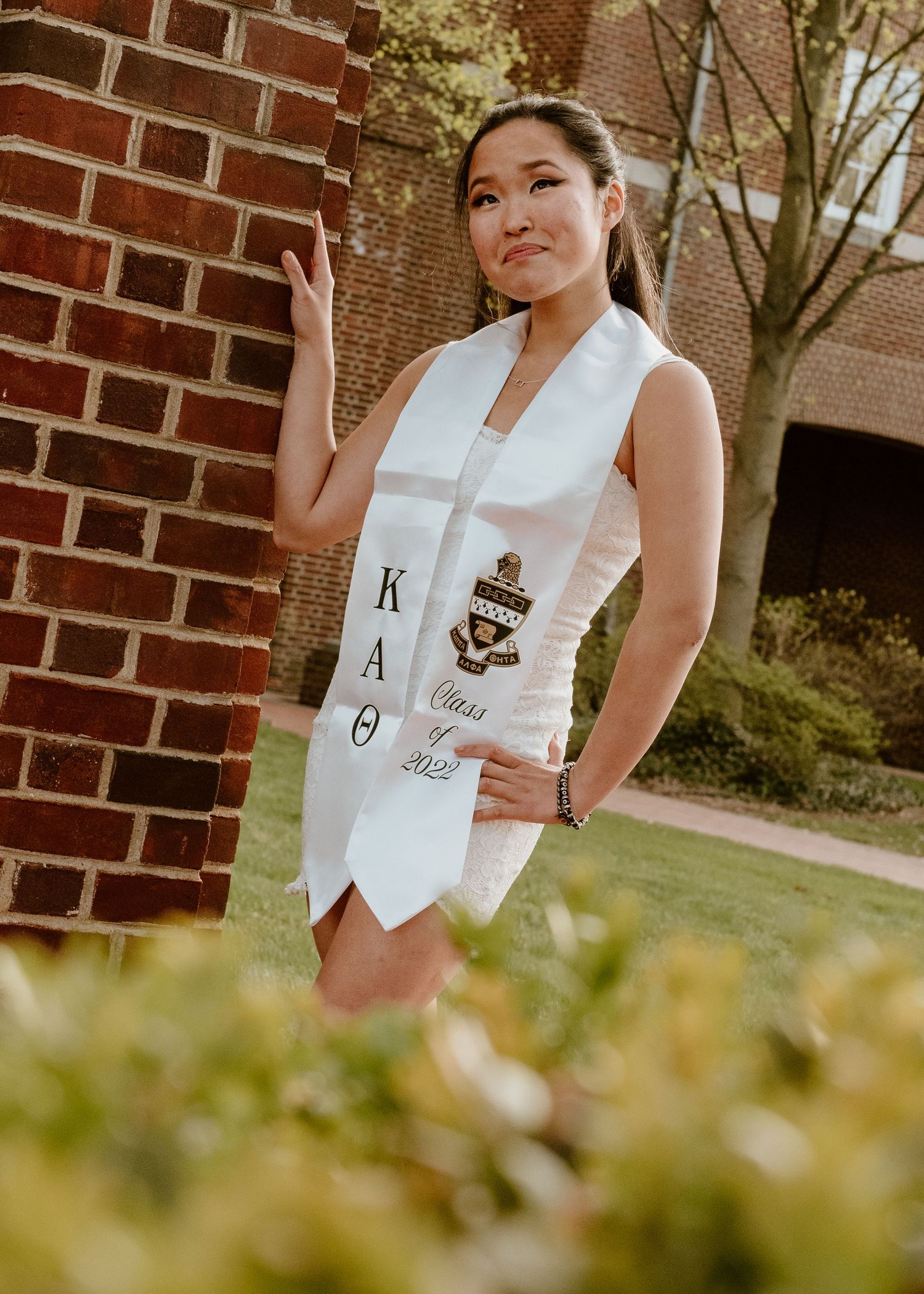 Casual outdoor portraits by a brick wall featuring white vest with decorative details and emblems.