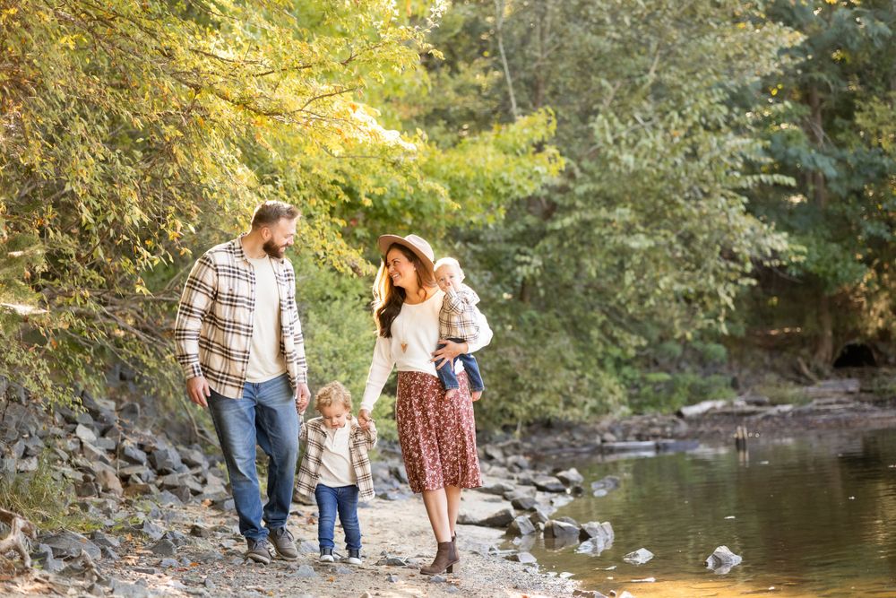 Family walking together along rocky creek bank in autumn setting.