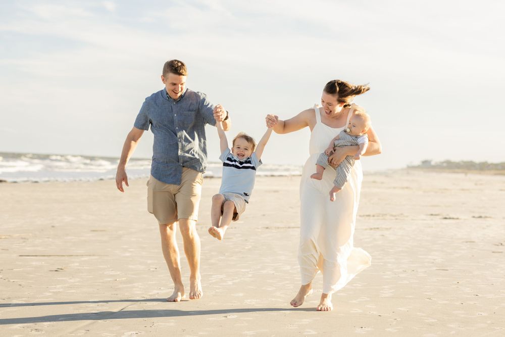 A family enjoys a playful moment together on a sunny beach.