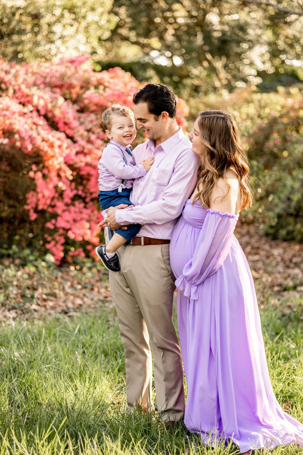 A springtime family portrait with blooming pink azaleas in a garden setting.