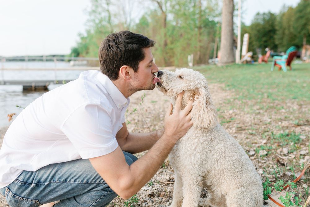 A couple plays with their small fluffy dog in a park setting.