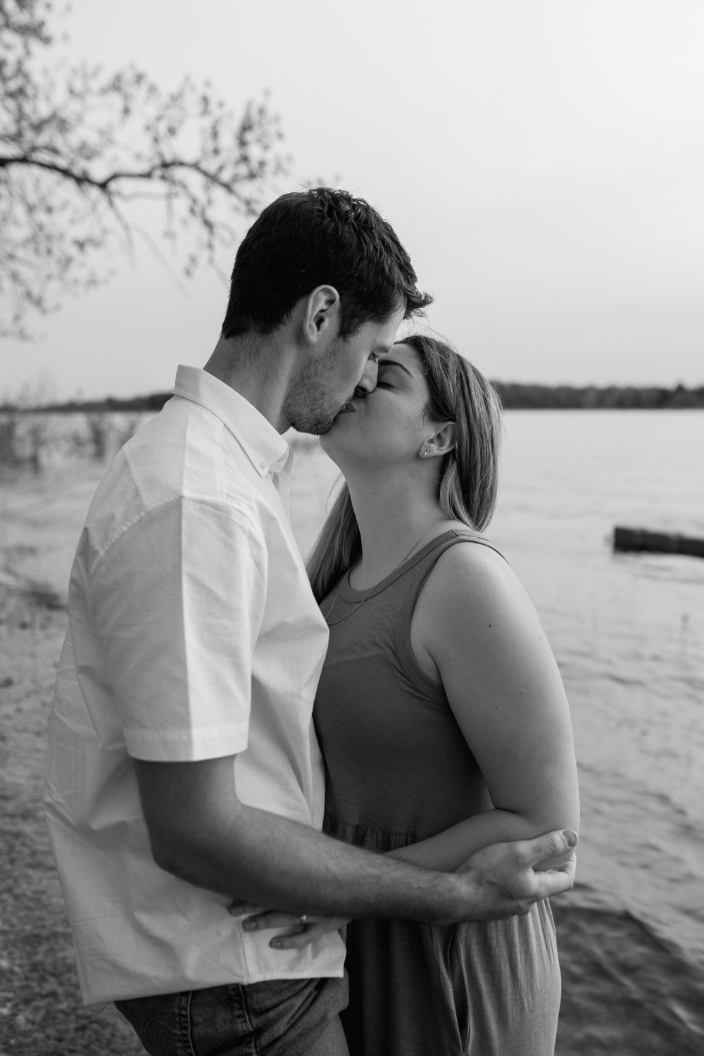 A couple shares tender moments against a lakeside backdrop.