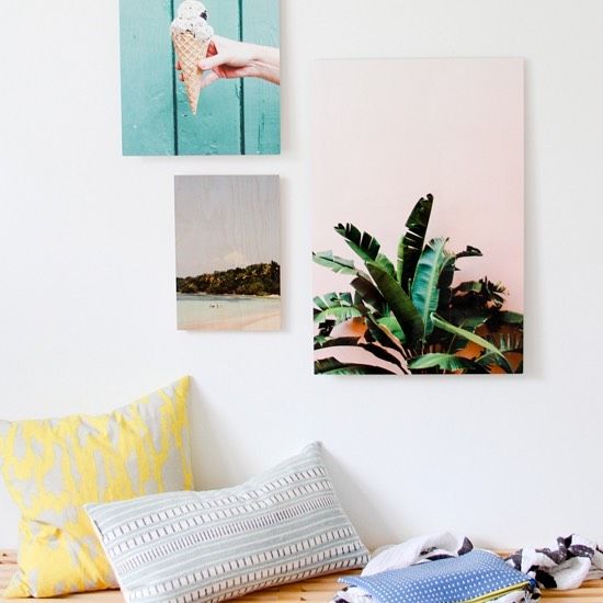Canvas wall arts scatted on a white wall and patterned cushions on the bottom of the photo to add some depth