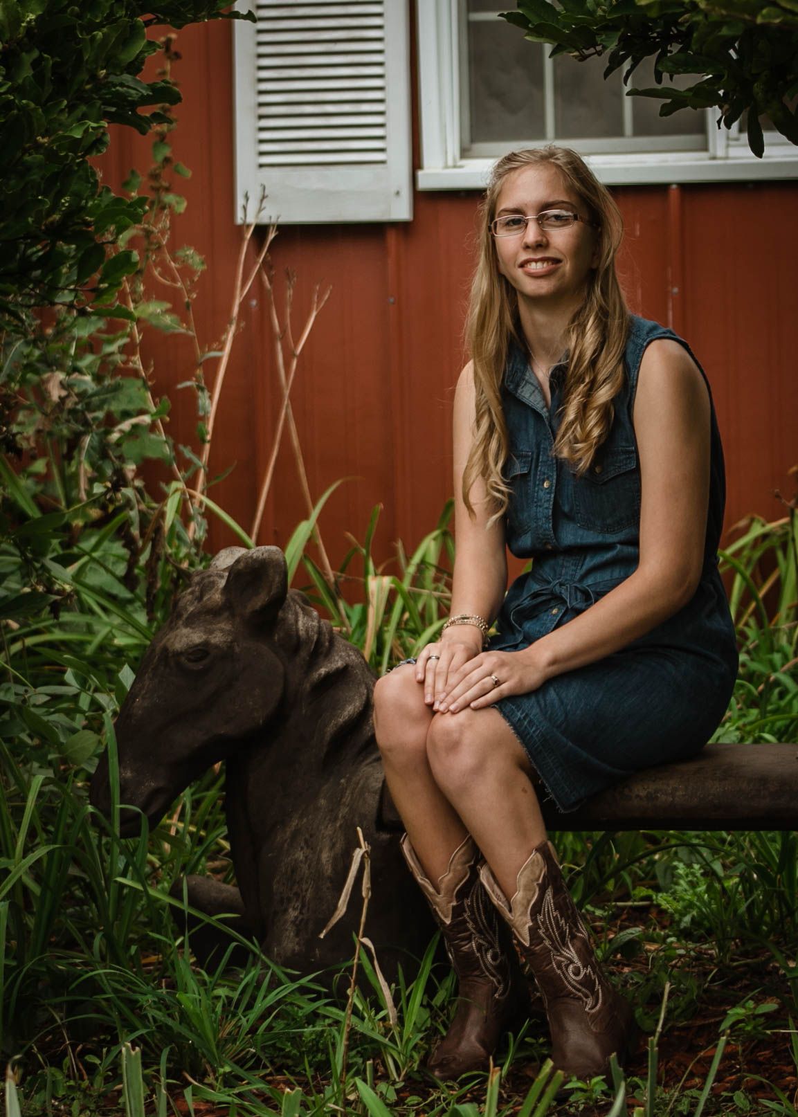 Beautiful young lady sitting on a gorgeous horse bench outside the Stars Barn in Sioux City, IA for her senior pictures.