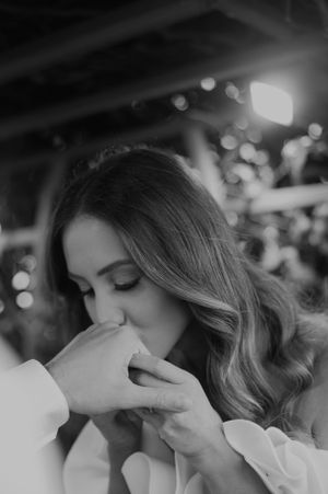 Black and white intimate moment captured during wedding ceremony with bokeh lights.