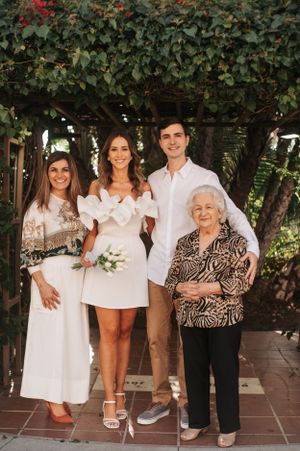 A family portrait session outdoors with everyone dressed in white and beige tones.
