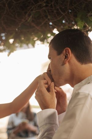 Close up view of someone kissing a hand during an intimate wedding moment with bokeh lights in background.