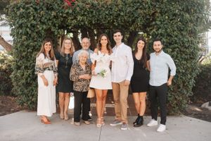 Group photo of family members lined up against a hedge wall with coordinated outfits.