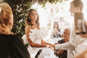 Intimate outdoor wedding ceremony with participants gathered under greenery.
