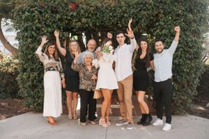 Cheerful group photo with everyone jumping and posing against an outdoor garden backdrop.