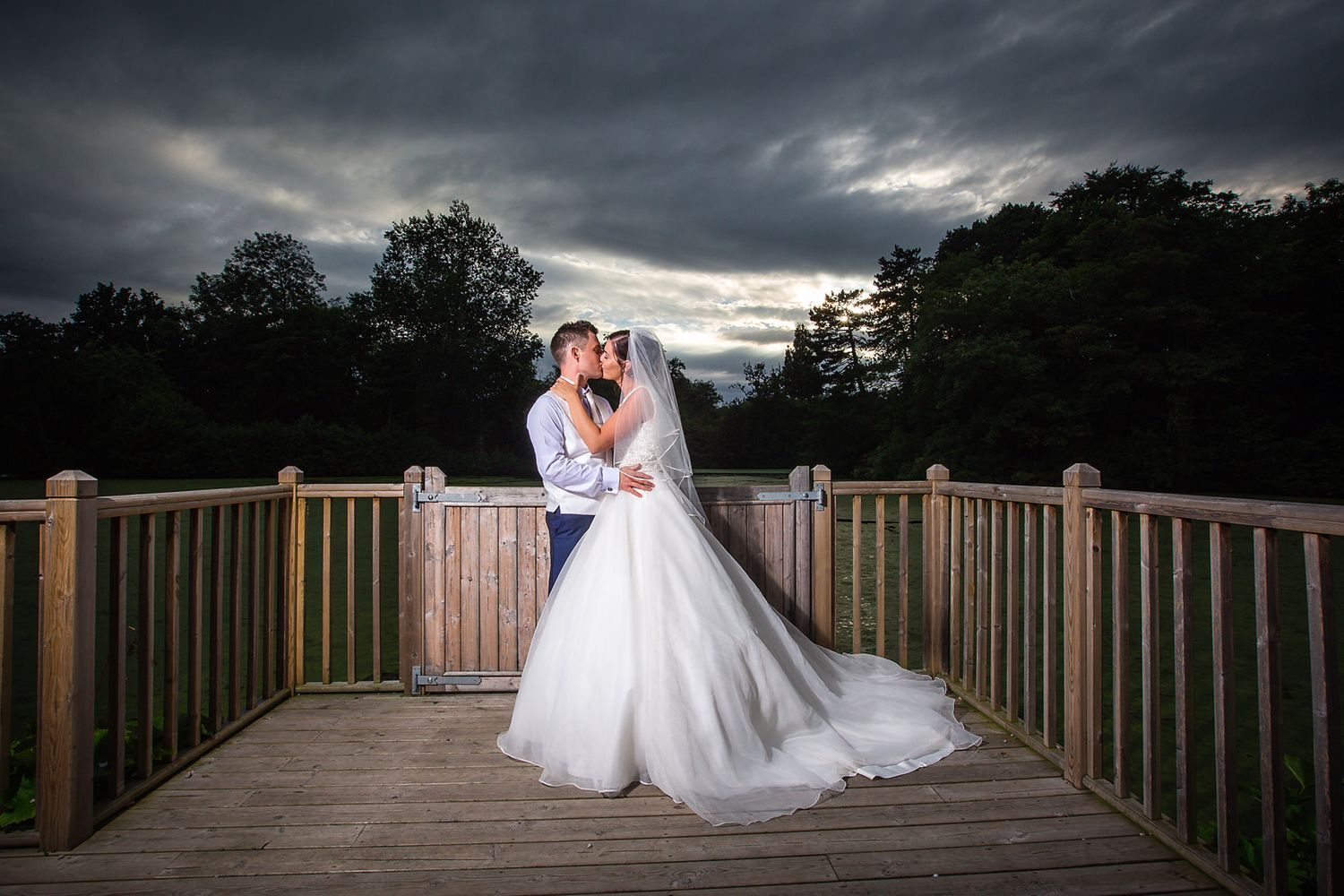Bride kisses her groom on the waterside marquee at night on their Thornton Manor wedding celebration