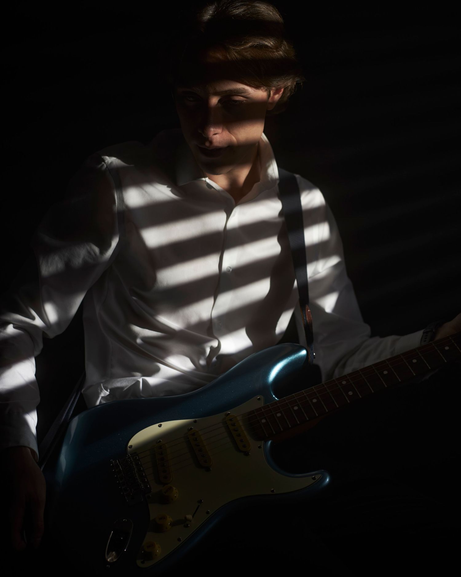 man in dark room holding guitar