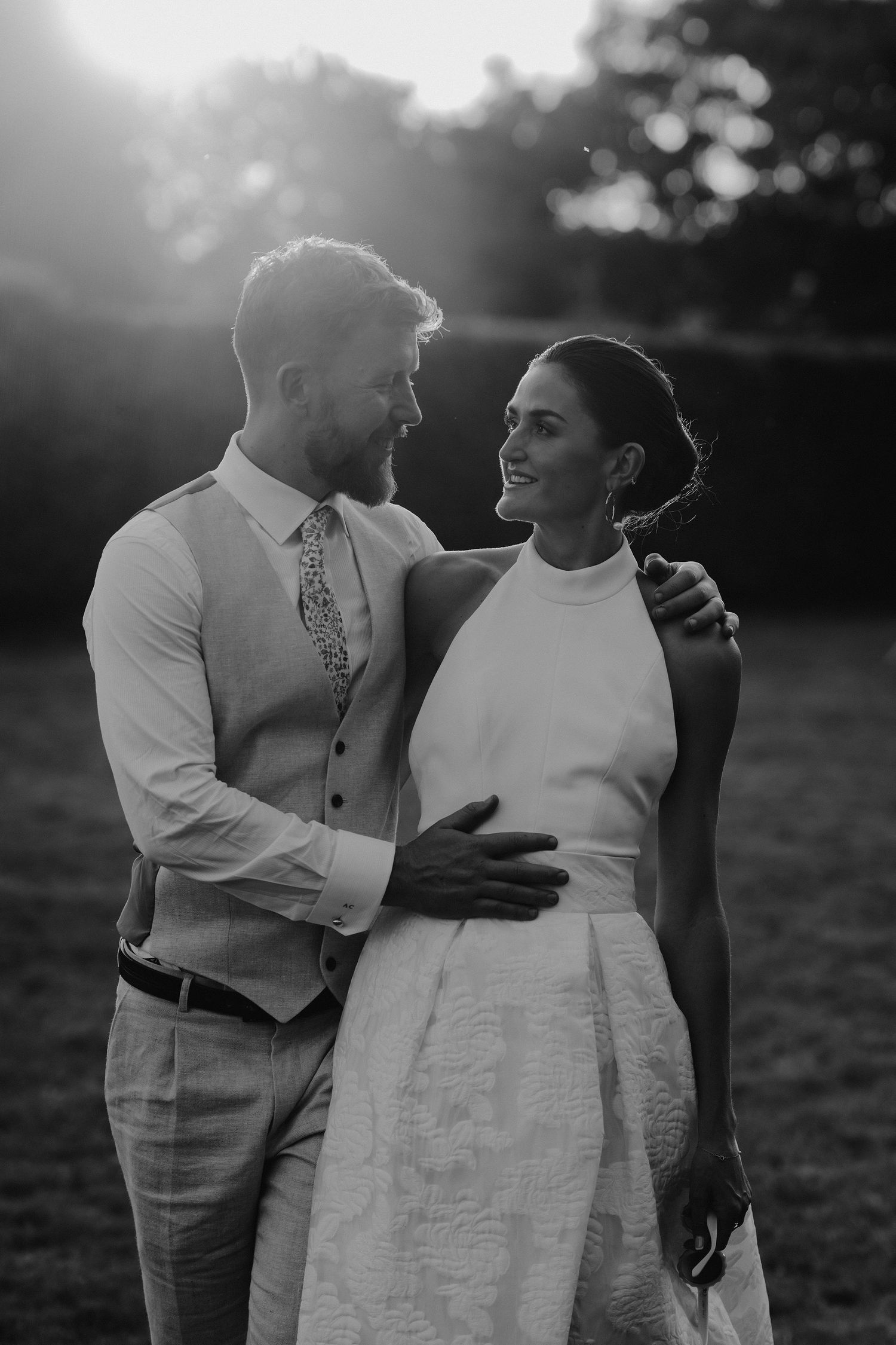 groom holding bride as they walk across lawn at marquee wedding in islip in oxfordshire