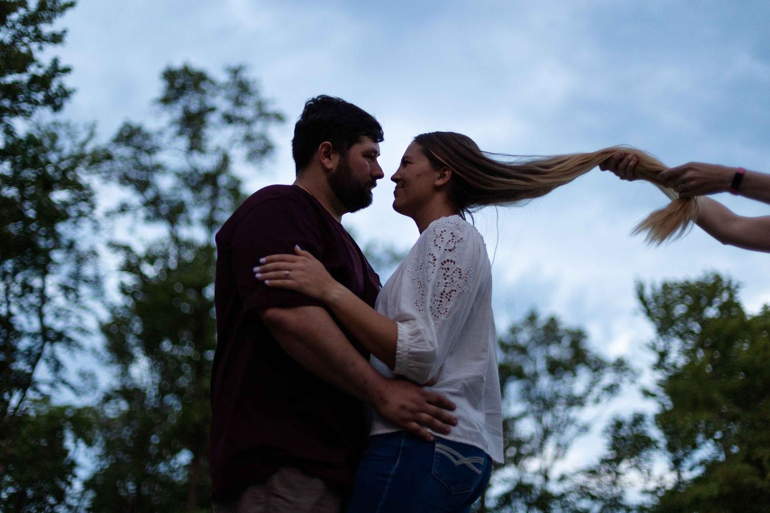 A romantic silhouette of a couple embracing at sunset in a park setting.
