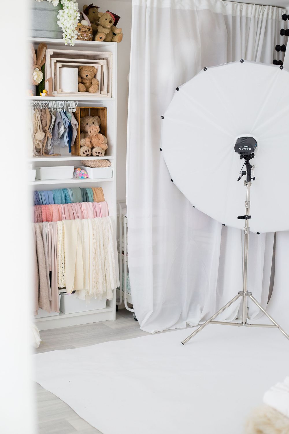 Professional photography studio setup with white backdrop, lighting equipment and organized props.