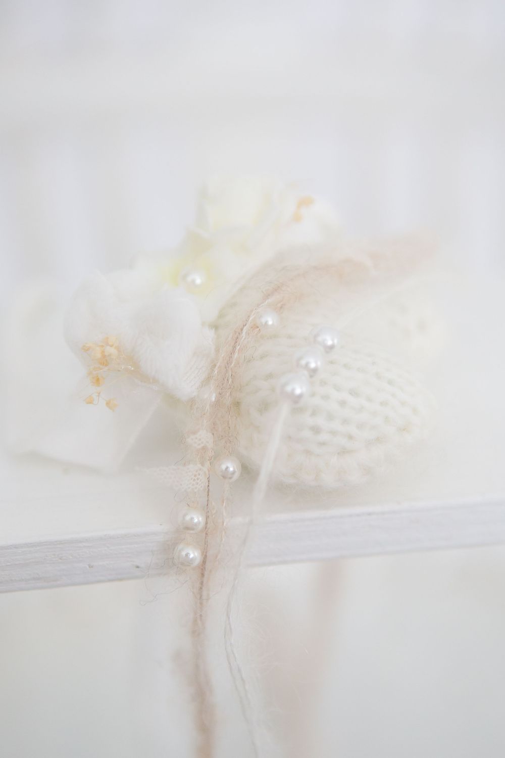 Delicate white hair accessory with pearl details and soft fabric accents.