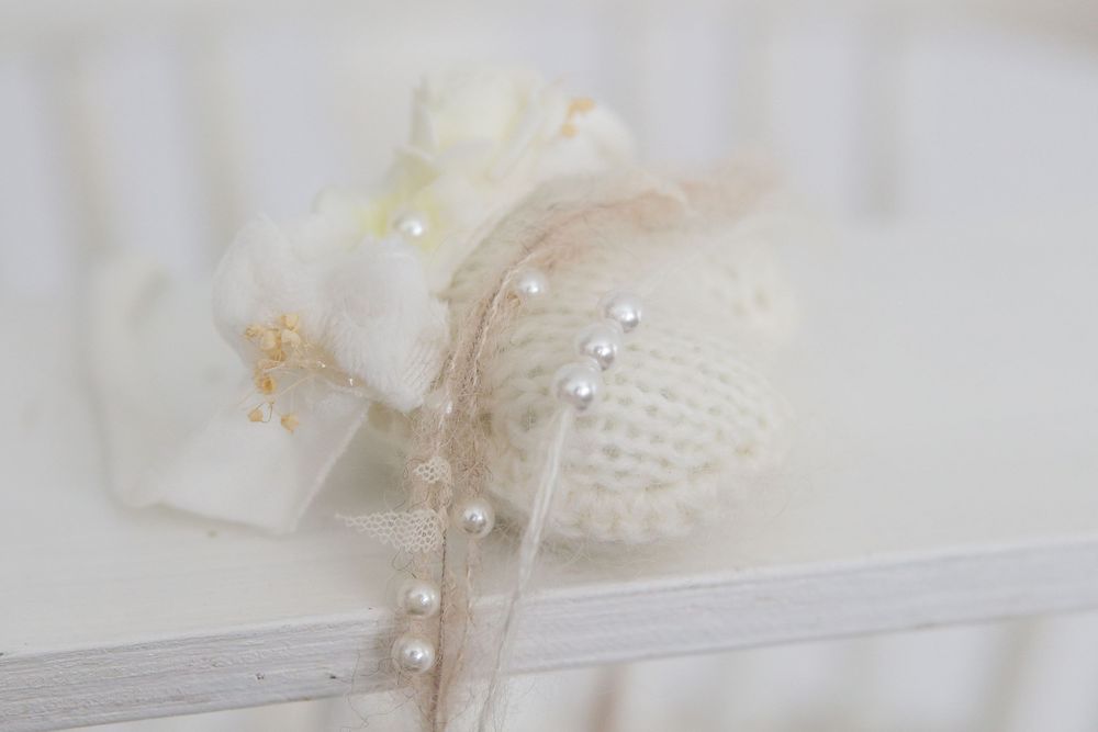 Dreamy close-up of white lace and pearl details on fabric.