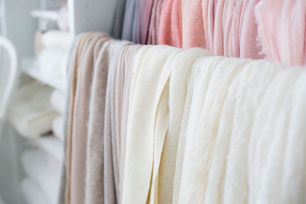 Soft pastel fabrics hanging in a row showing delicate pink and white tones.
