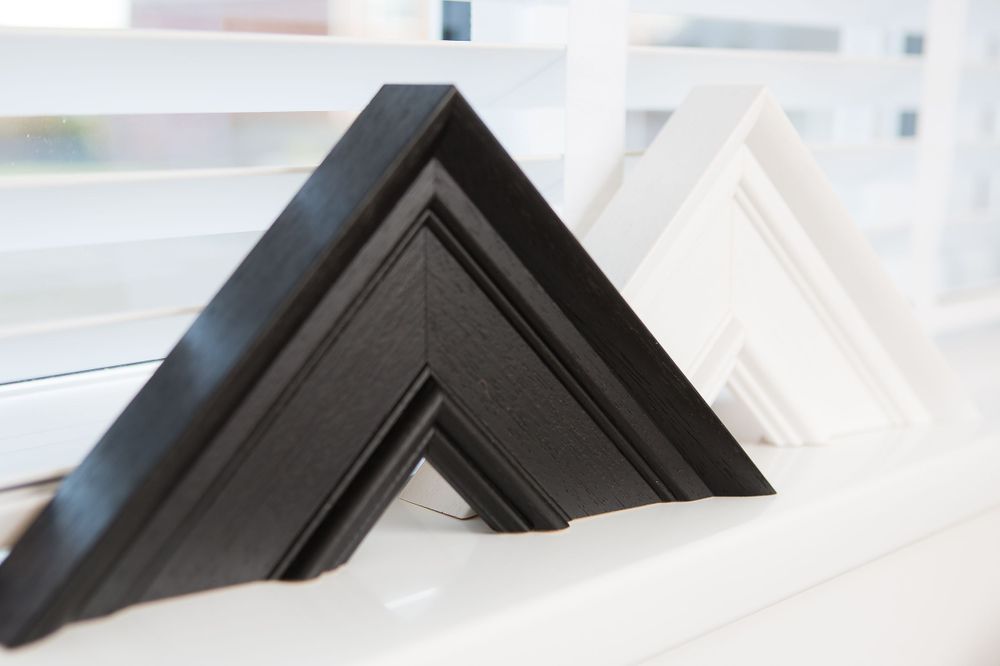 Black and white picture frame corners displayed on a white shelf.