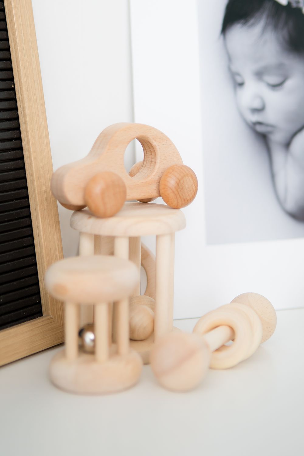 Wooden toy car and rattle displayed on a white surface with minimal decor.
