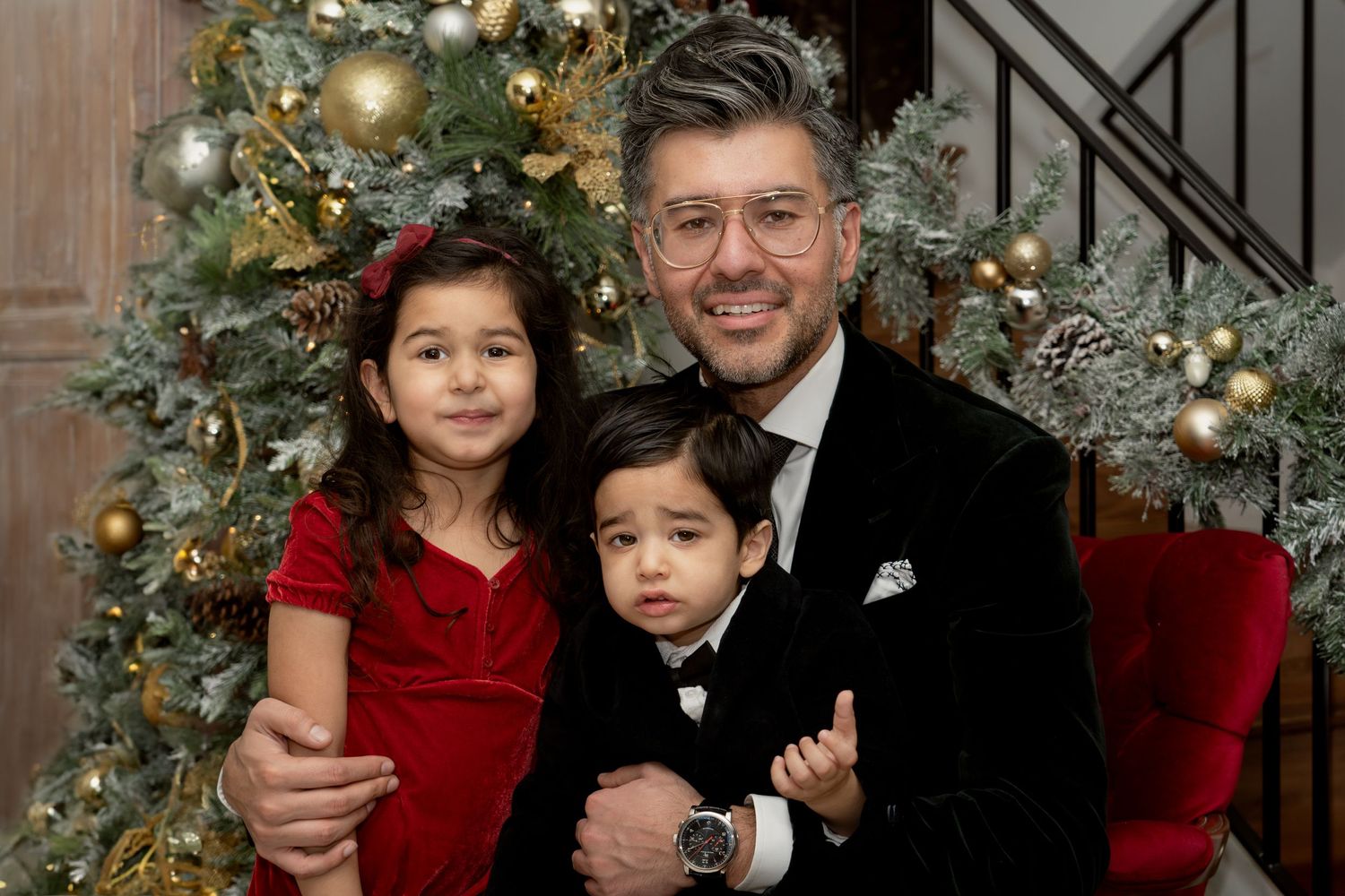 Elegant family photo with decorated Christmas tree and formal attire.