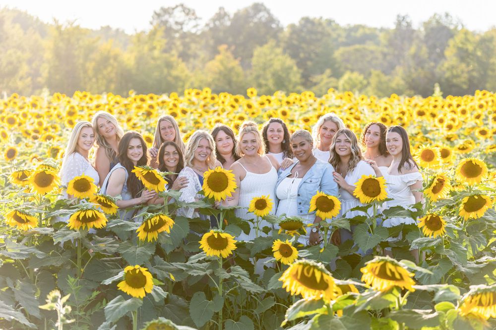 group of stylist women wearing white and denim in a sunflower field at sunset in clayton Monroeville new jersey