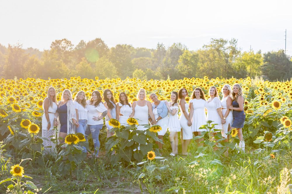 group of stylist women wearing white and denim in a sunflower field at sunset in clayton Monroeville new jersey