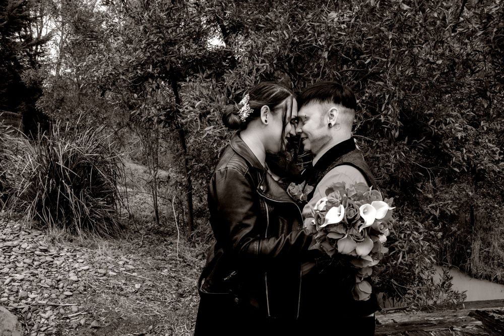 Bride in black dress and groom in black vestBlack and white artistic photo series captured in a natural outdoor setting with dark contrasts.