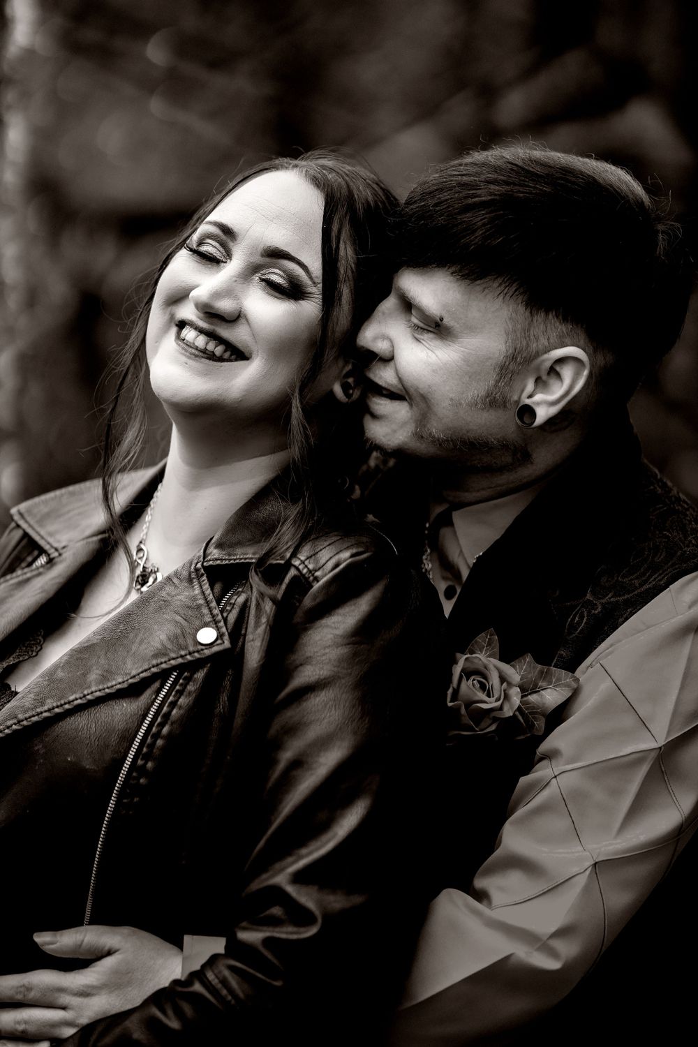 Bride in black dress and groom in black vest in A black and white portrait capturing a joyful moment